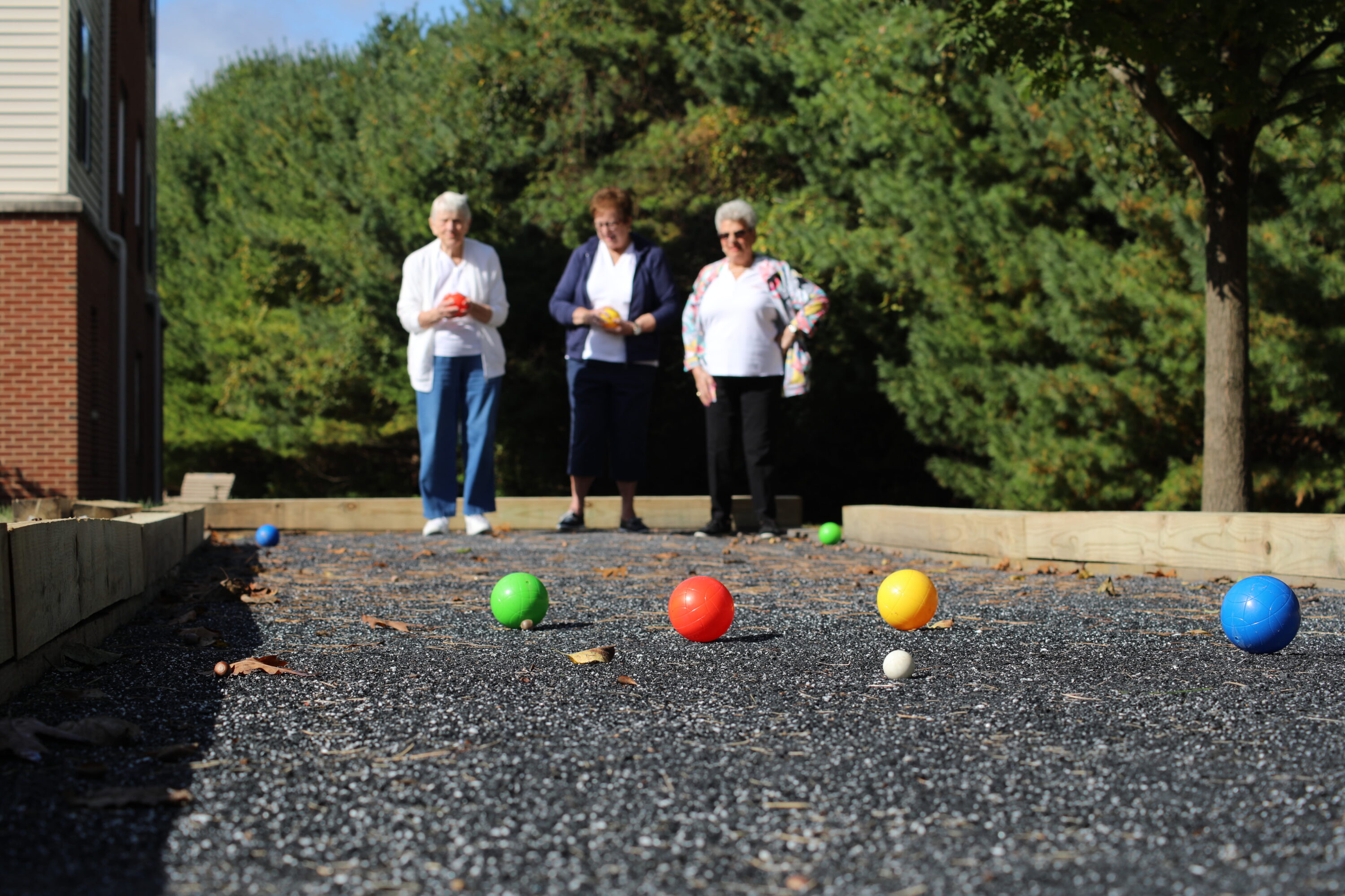 Three women playing bocce on outdoor court