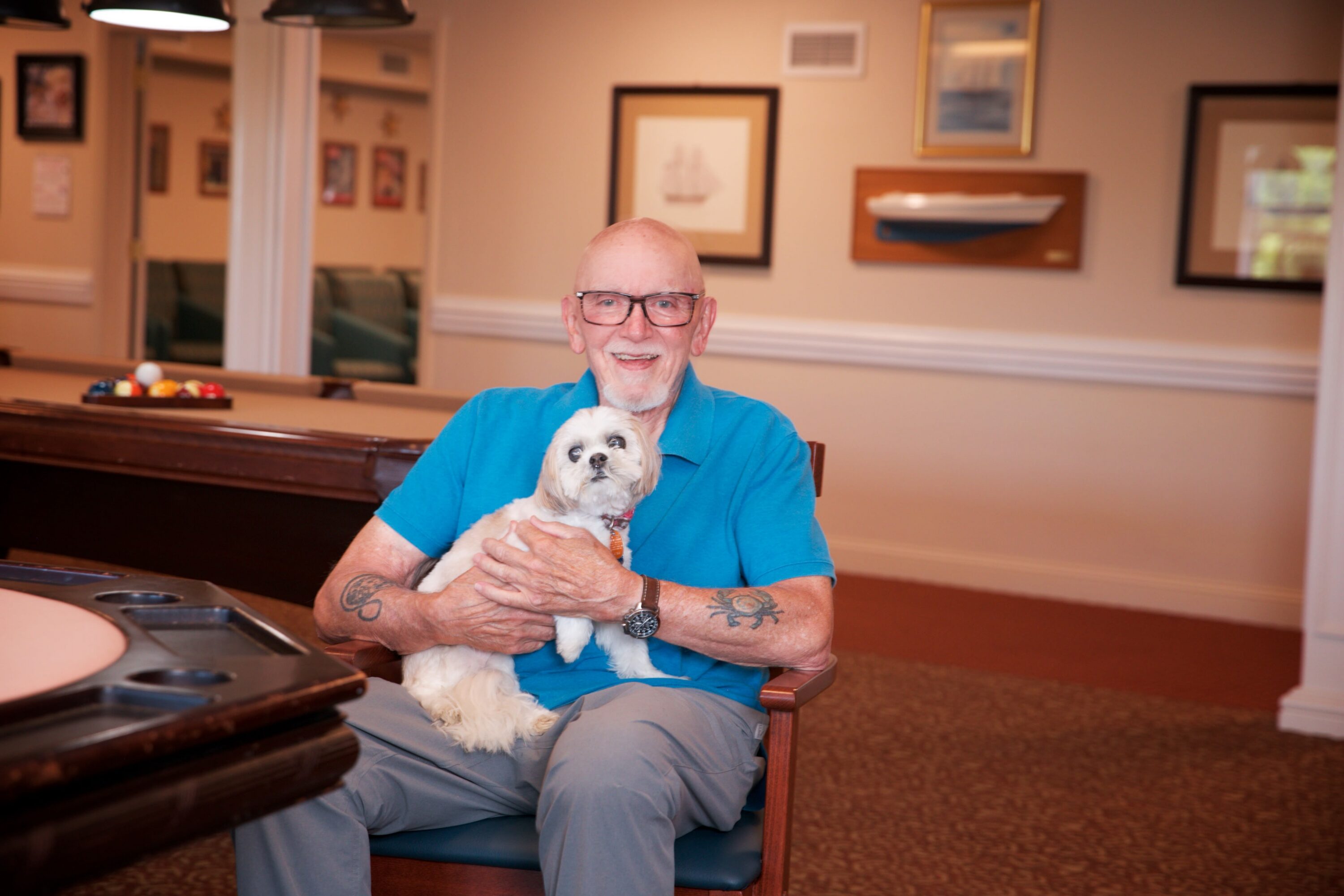 Elderly man holding small dog indoors
