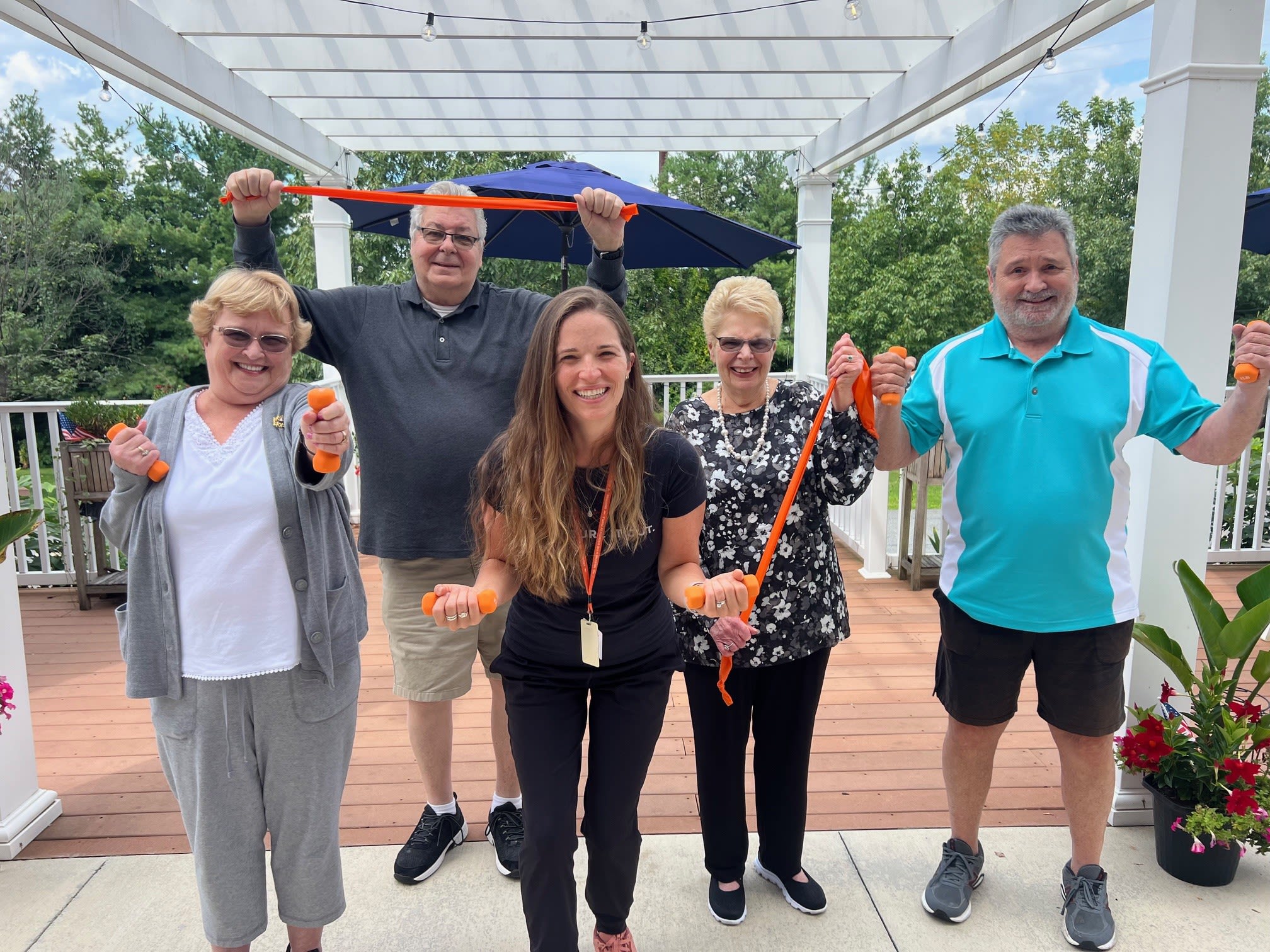 Group exercising with dumbbells and resistance bands outdoors