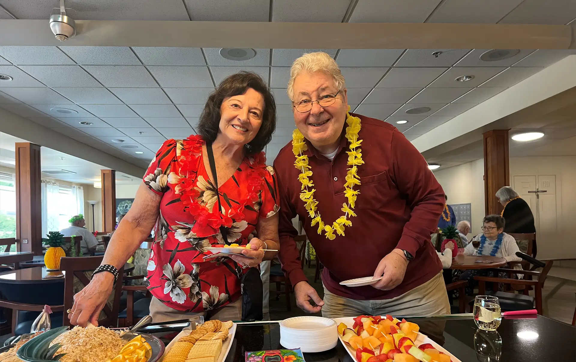 Smiling couple wearing leis at buffet table