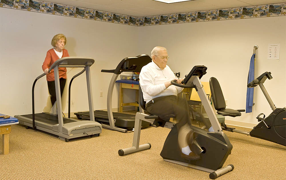 Seniors exercising on treadmill and stationary bike indoors