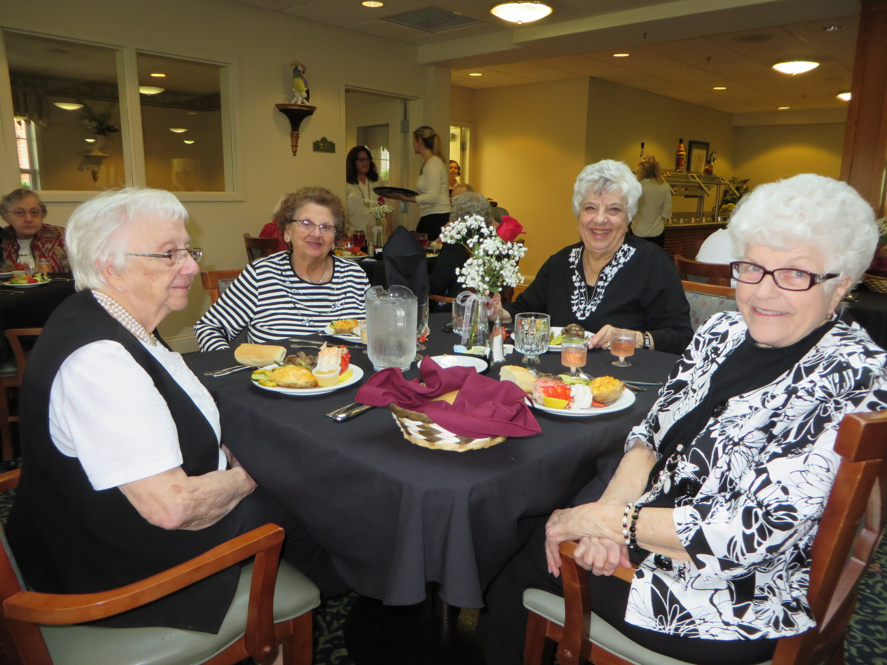 Four elderly women dining together at restaurant table
