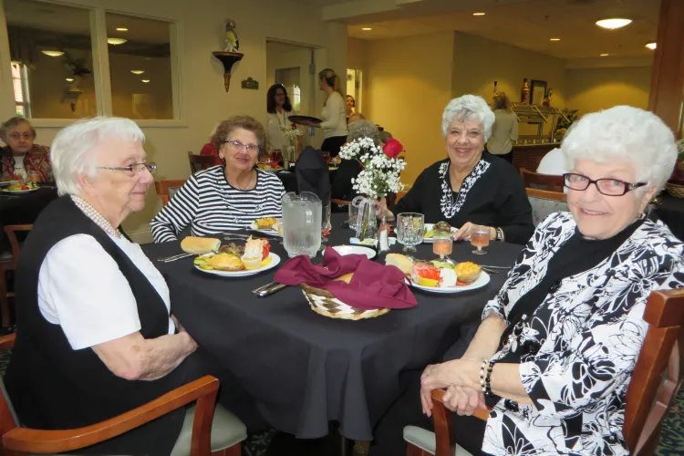 Four elderly women dining together at table