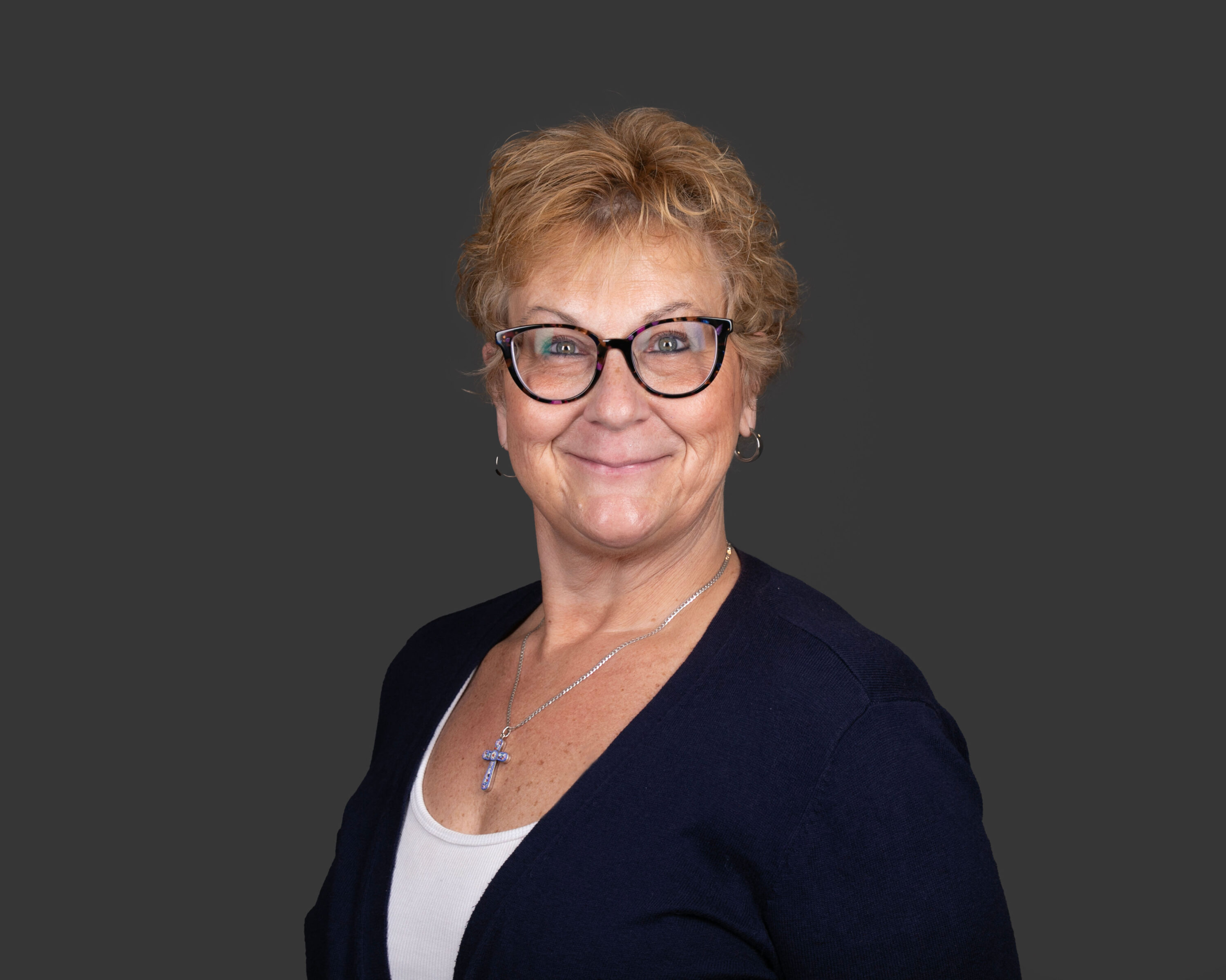 Smiling woman with glasses against gray background
