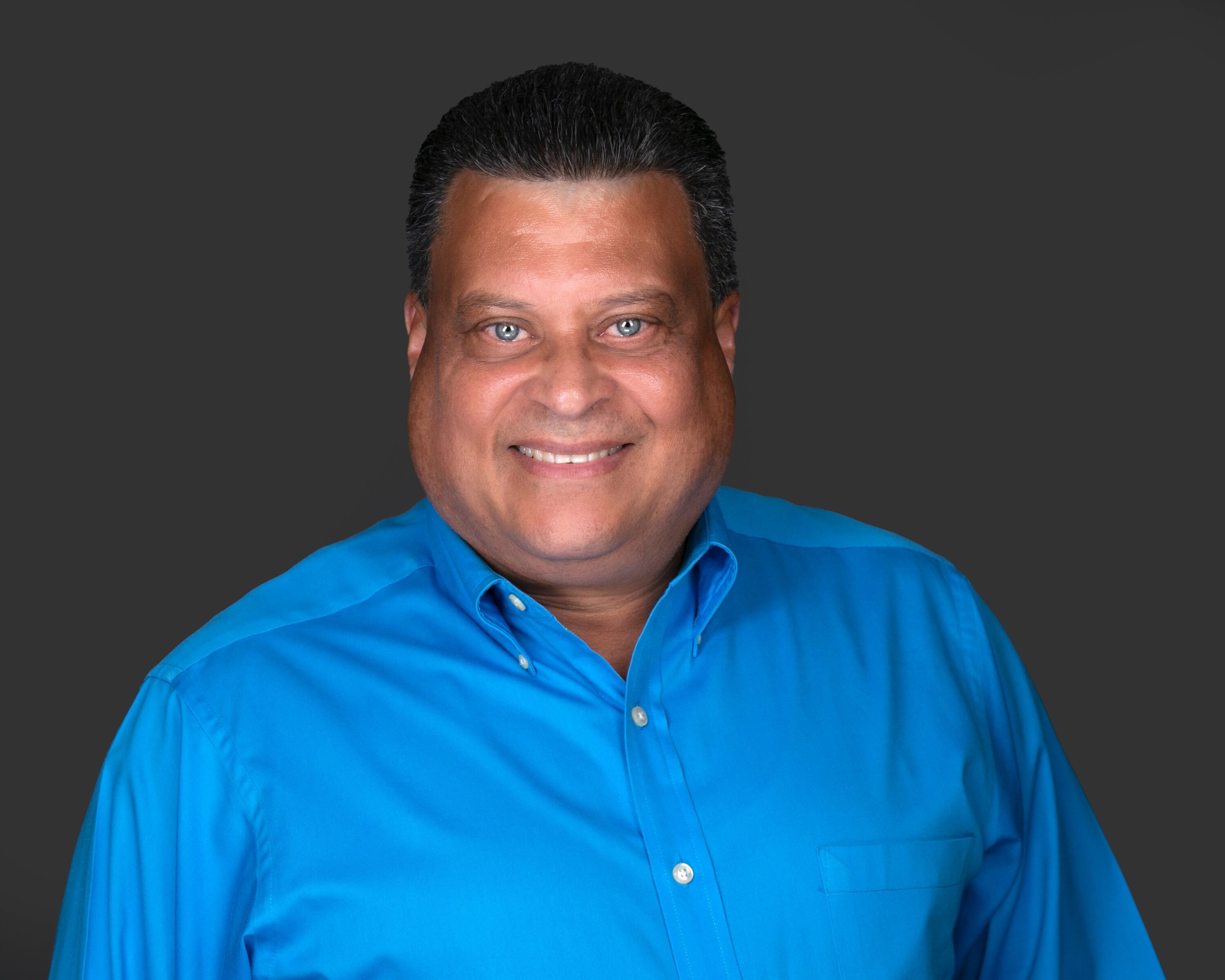Smiling man in blue shirt on dark background