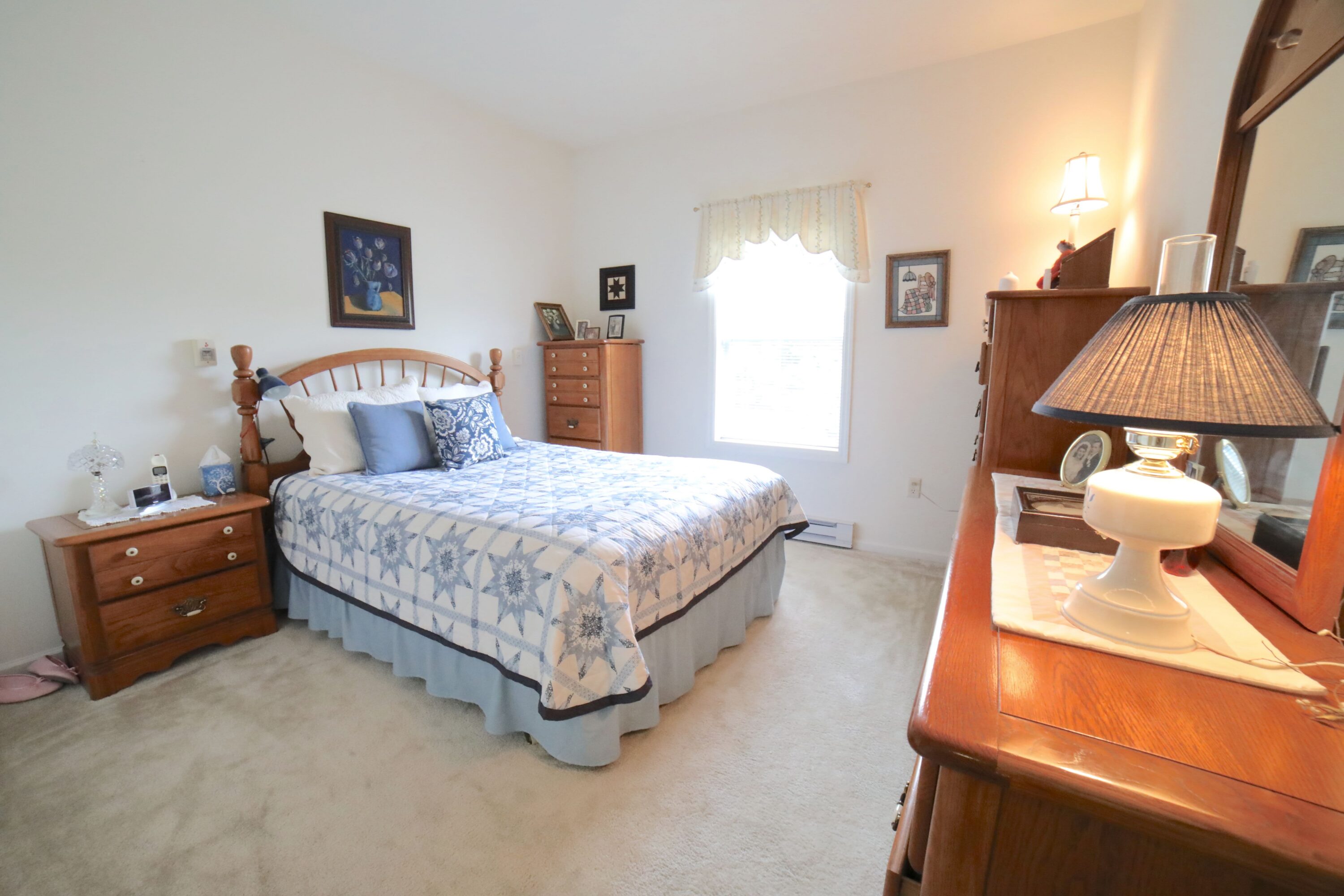 Cozy bedroom with wooden furniture and quilted bed