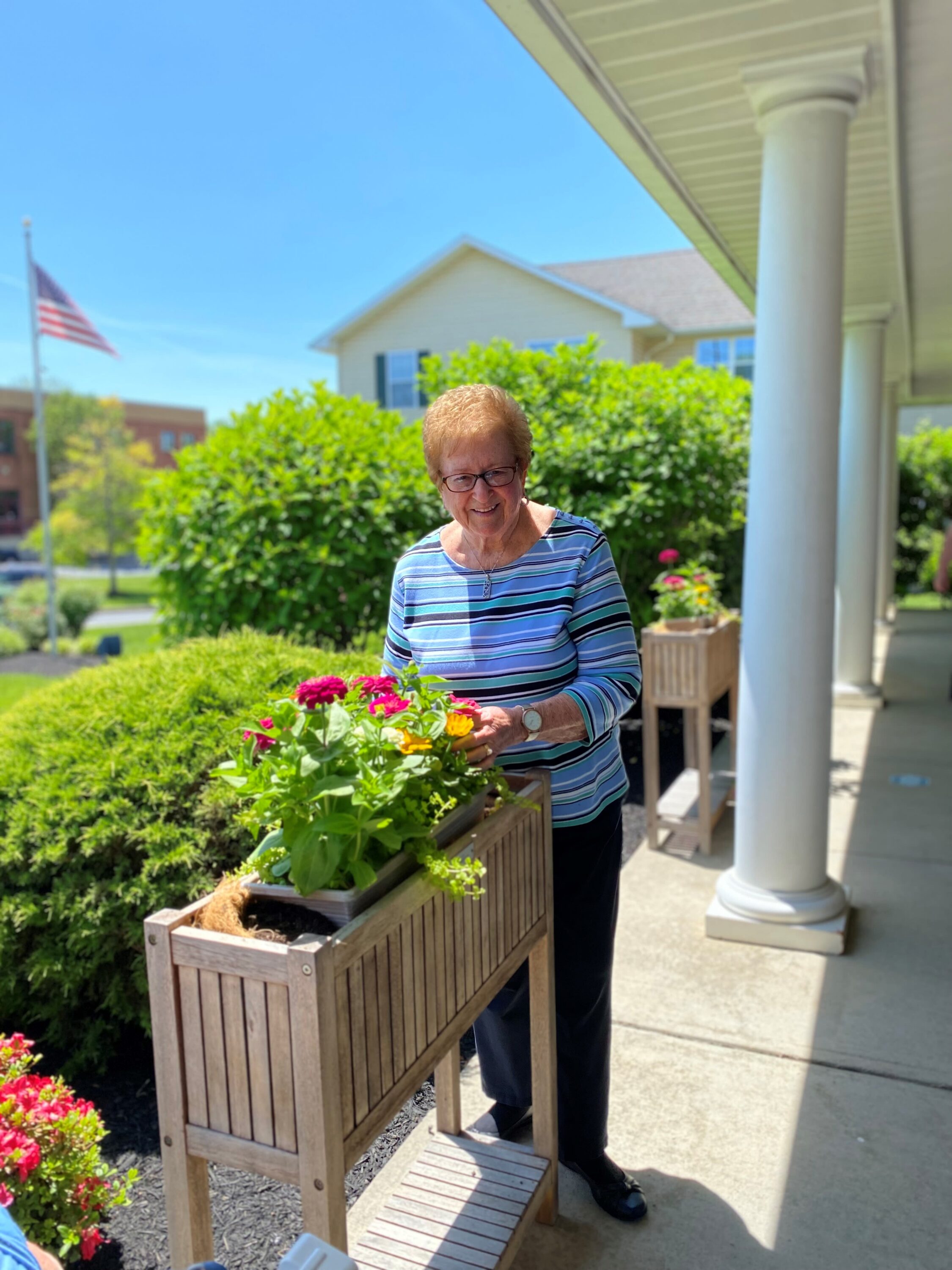 Elderly woman tending flowers on sunny porch