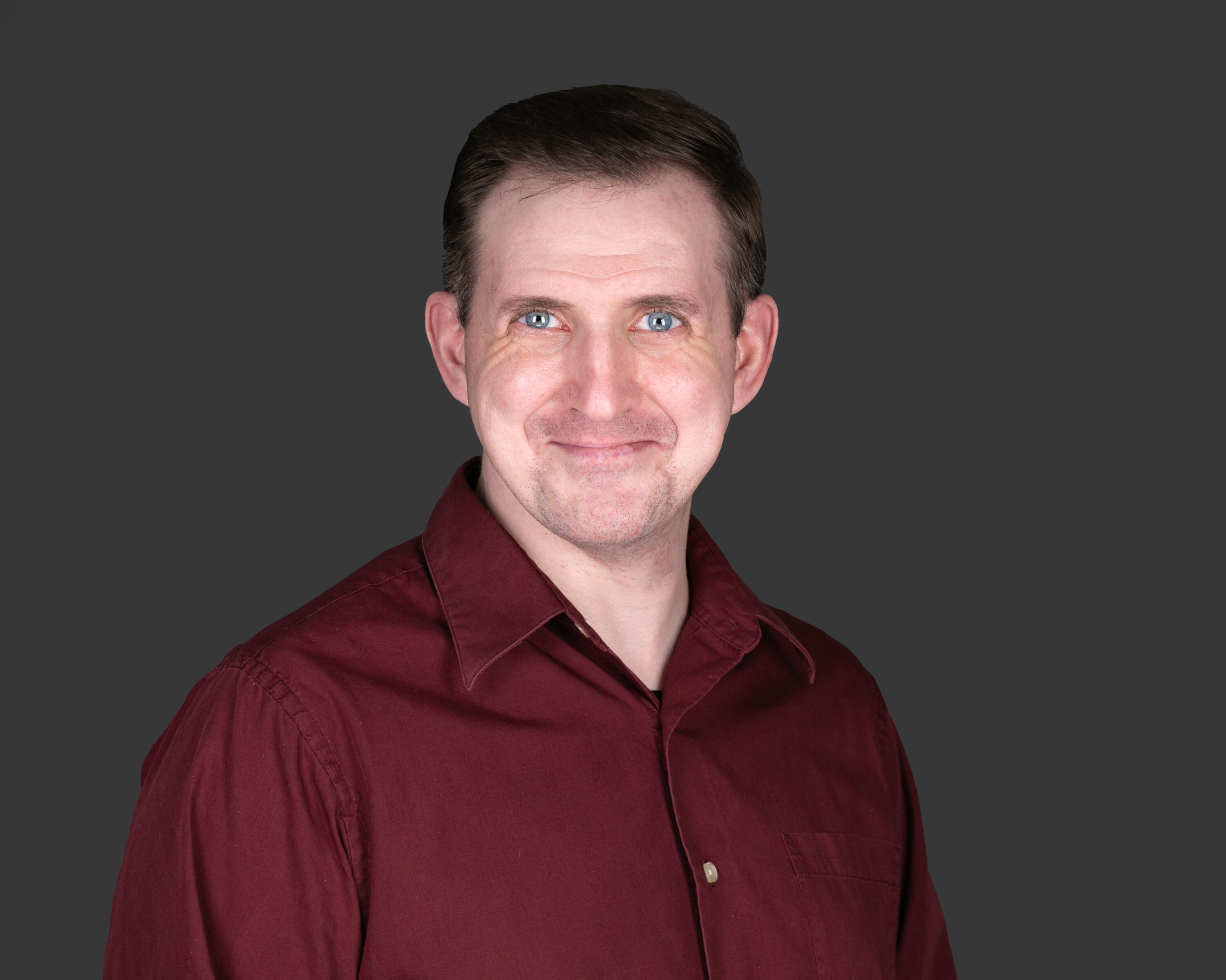 Man in maroon shirt against gray background