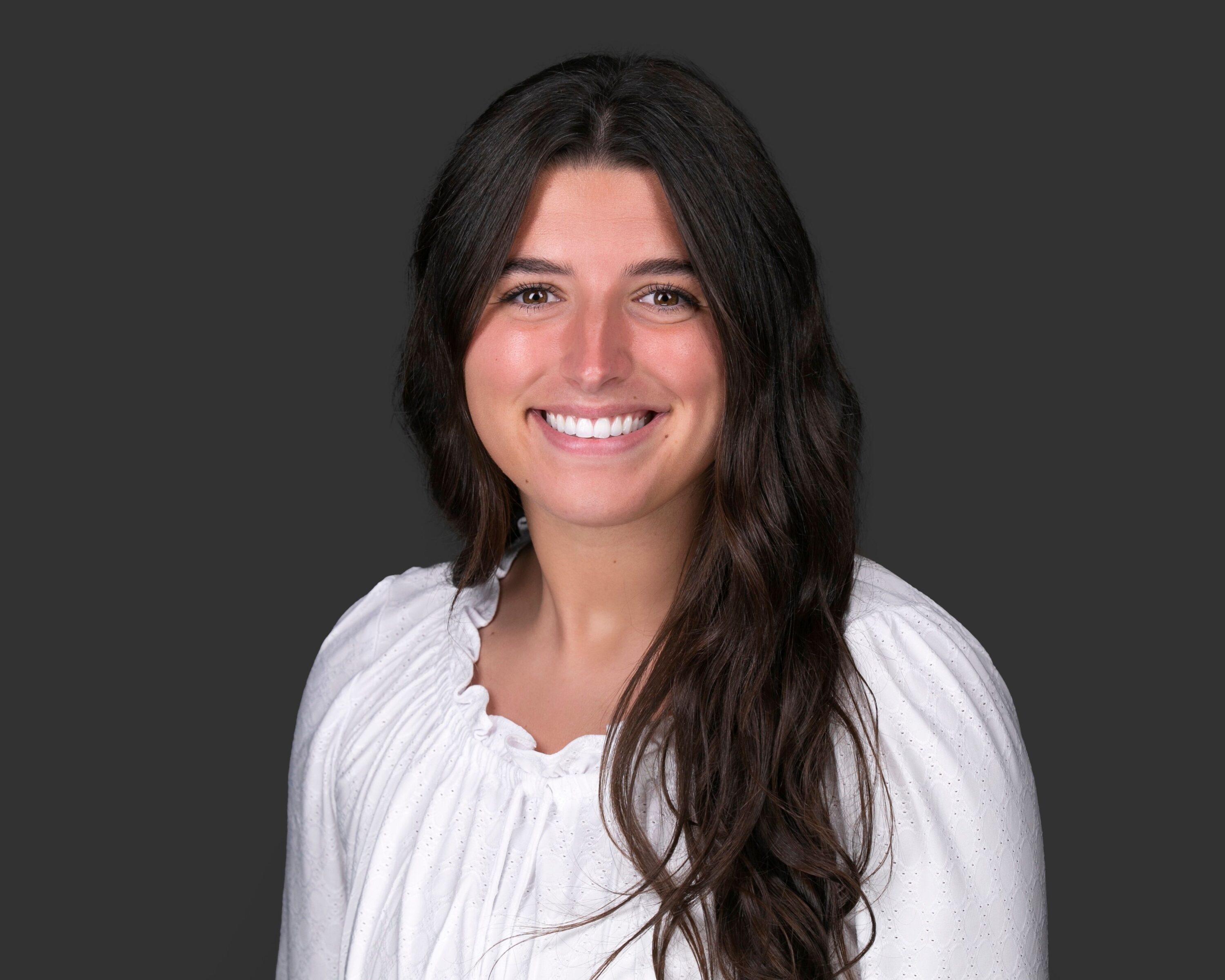 Smiling woman in white blouse against gray background